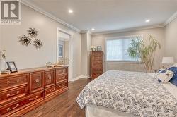 Bedroom with ornamental molding and dark wood-type flooring - 