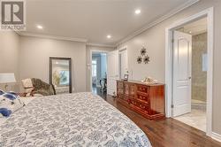 Bedroom featuring ensuite bathroom, ornamental molding, and dark wood-type flooring - 