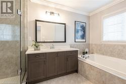 Bathroom featuring tile patterned flooring, vanity, separate shower and tub, and ornamental molding - 