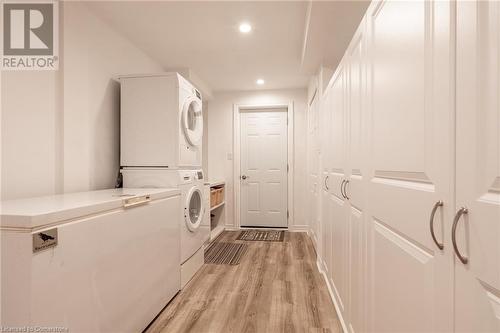 Laundry room featuring light hardwood / wood-style floors and stacked washing maching and dryer - 26 Summerberry Way, Hamilton, ON - Indoor Photo Showing Laundry Room