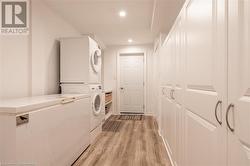 Laundry room featuring light hardwood / wood-style floors and stacked washing maching and dryer - 