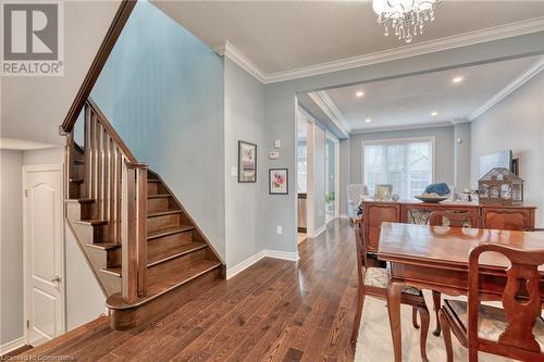 Dining area featuring a textured ceiling, crown molding, a notable chandelier, and hardwood / wood-style flooring - 26 Summerberry Way, Hamilton, ON - Indoor