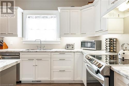 Kitchen featuring light stone counters, sink, white cabinetry, and stainless steel appliances - 175 Mcnab St, Stratford, ON - Indoor Photo Showing Kitchen With Double Sink