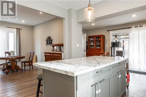 Kitchen featuring light stone countertops, a center island, dark wood-type flooring, and decorative light fixtures - 175 Mcnab St, Stratford, ON - Indoor