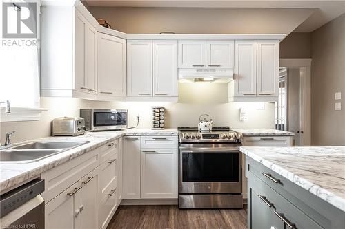 Kitchen featuring white cabinetry, sink, light stone counters, dark hardwood / wood-style floors, and appliances with stainless steel finishes - 175 Mcnab St, Stratford, ON - Indoor Photo Showing Kitchen With Double Sink With Upgraded Kitchen