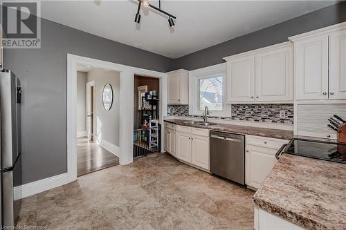 Kitchen featuring sink, white cabinetry, backsplash, and appliances with stainless steel finishes - 20 Sarah Street, Brantford, ON - Indoor Photo Showing Kitchen With Double Sink