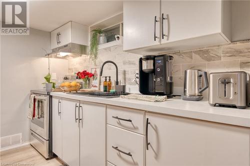 Kitchen with decorative backsplash, sink, white cabinets, light hardwood / wood-style floors, and stainless steel electric range oven - 99 East 36Th Street, Hamilton, ON - Indoor Photo Showing Kitchen