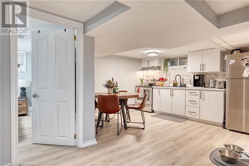 Kitchen featuring backsplash, white cabinets, sink, appliances with stainless steel finishes, and light hardwood / wood-style floors - 99 East 36Th Street, Hamilton, ON - Indoor Photo Showing Kitchen