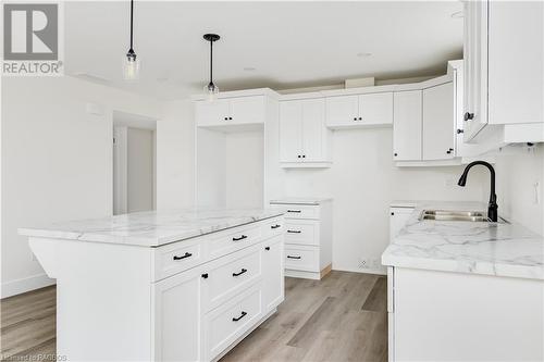 Kitchen featuring decorative light fixtures, a kitchen island, white cabinetry, and light hardwood / wood-style flooring - 323 Mclean Crescent, Saugeen Shores, ON - Indoor Photo Showing Kitchen