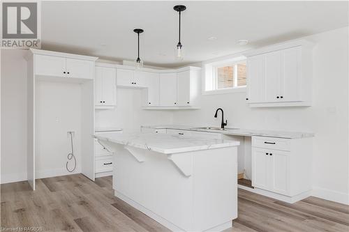 Kitchen with white cabinetry, sink, hanging light fixtures, a kitchen island, and light wood-type flooring - 323 Mclean Crescent, Saugeen Shores, ON - Indoor Photo Showing Kitchen