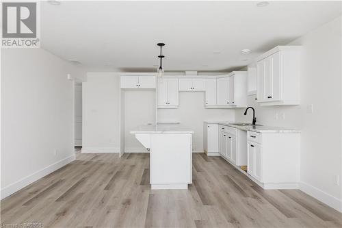 Kitchen with sink, light hardwood / wood-style flooring, white cabinets, a center island, and hanging light fixtures - 323 Mclean Crescent, Saugeen Shores, ON - Indoor Photo Showing Kitchen