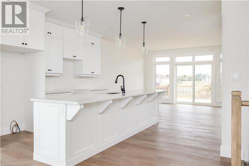 Kitchen featuring light wood-type flooring, sink, a center island with sink, white cabinets, and hanging light fixtures - 323 Mclean Crescent, Saugeen Shores, ON - Indoor Photo Showing Kitchen