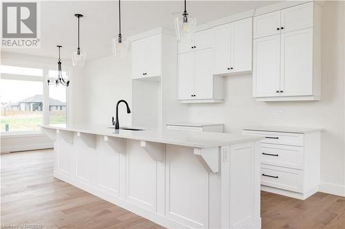 Kitchen with a kitchen island with sink, white cabinets, and hanging light fixtures - 323 Mclean Crescent, Saugeen Shores, ON - Indoor Photo Showing Kitchen