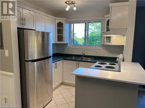 Kitchen featuring backsplash, white cabinetry, sink, and stainless steel refrigerator - 2373 King Street E Unit# 48, Hamilton, ON - Indoor Photo Showing Kitchen With Double Sink