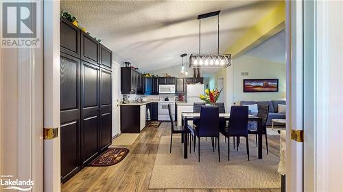 Dining room featuring a textured ceiling, light wood-type flooring, and lofted ceiling - 69 St James Place, Wasaga Beach, ON - Indoor Photo Showing Other Room