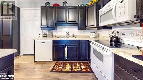 Kitchen featuring tasteful backsplash, white appliances, sink, and light hardwood / wood-style flooring - 69 St James Place, Wasaga Beach, ON - Indoor Photo Showing Kitchen With Double Sink