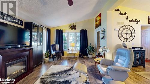 Living area with wood-type flooring, a textured ceiling, and vaulted ceiling - 69 St James Place, Wasaga Beach, ON - Indoor Photo Showing Living Room With Fireplace