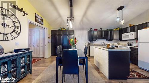 Kitchen featuring vaulted ceiling, hanging light fixtures, white appliances, and light wood-type flooring - 69 St James Place, Wasaga Beach, ON - Indoor Photo Showing Kitchen