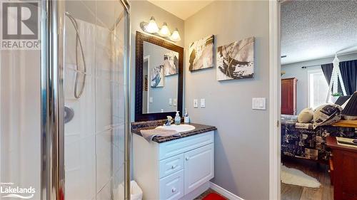 Bathroom with hardwood / wood-style flooring, vanity, a shower with door, and a textured ceiling - 69 St James Place, Wasaga Beach, ON - Indoor Photo Showing Bathroom