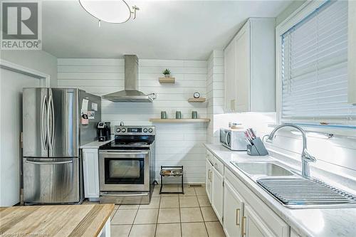 Kitchen with white cabinetry, sink, wall chimney exhaust hood, stainless steel appliances, and light tile patterned floors - 72 Elgin Street S, Cambridge, ON - Indoor Photo Showing Kitchen With Upgraded Kitchen