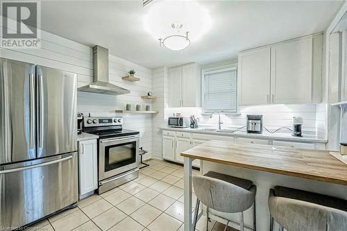 Kitchen featuring appliances with stainless steel finishes, wall chimney range hood, light tile patterned floors, white cabinets, and butcher block countertops - 72 Elgin Street S, Cambridge, ON - Indoor Photo Showing Kitchen With Upgraded Kitchen