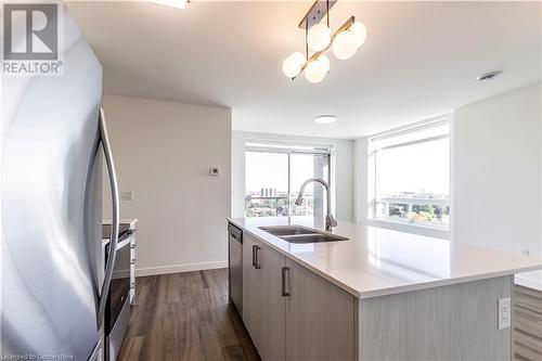 Kitchen with stainless steel appliances, dark wood-type flooring, sink, decorative light fixtures, and an island with sink - 479 Charlton Avenue E Unit# 404, Hamilton, ON - Indoor Photo Showing Kitchen With Double Sink