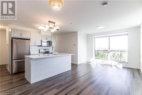 Kitchen featuring appliances with stainless steel finishes, dark hardwood / wood-style flooring, backsplash, sink, and decorative light fixtures - 479 Charlton Avenue E Unit# 404, Hamilton, ON - Indoor Photo Showing Kitchen With Stainless Steel Kitchen