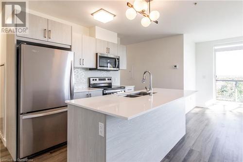 Kitchen featuring sink, stainless steel appliances, tasteful backsplash, wood-type flooring, and a kitchen island with sink - 479 Charlton Avenue E Unit# 404, Hamilton, ON - Indoor Photo Showing Kitchen With Stainless Steel Kitchen With Double Sink