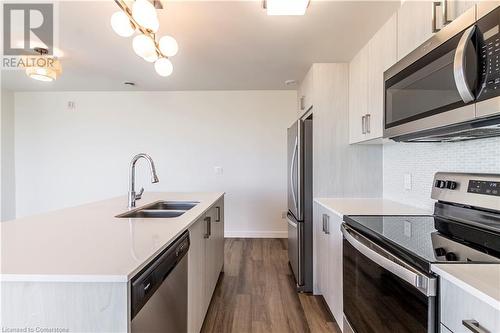 Kitchen featuring hardwood / wood-style floors, backsplash, an inviting chandelier, sink, and stainless steel appliances - 479 Charlton Avenue E Unit# 404, Hamilton, ON - Indoor Photo Showing Kitchen With Stainless Steel Kitchen With Double Sink With Upgraded Kitchen