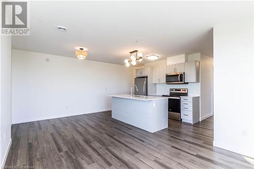 Kitchen featuring hanging light fixtures, stainless steel appliances, a kitchen island with sink, and dark wood-type flooring - 479 Charlton Avenue E Unit# 404, Hamilton, ON - Indoor Photo Showing Kitchen With Stainless Steel Kitchen