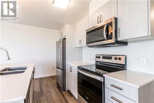 Kitchen with hardwood / wood-style floors, appliances with stainless steel finishes, backsplash, and sink - 479 Charlton Avenue E Unit# 404, Hamilton, ON - Indoor Photo Showing Kitchen With Stainless Steel Kitchen With Double Sink