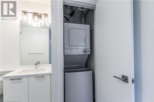 Washroom featuring stacked washing maching and dryer and sink - 479 Charlton Avenue E Unit# 404, Hamilton, ON - Indoor Photo Showing Laundry Room