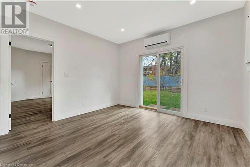 Living room in the ADU featuring hardwood / wood-style floors and a wall unit AC - 306 Paling Avenue, Hamilton, ON - Indoor Photo Showing Other Room