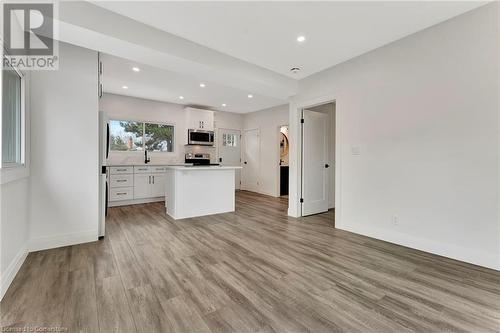 Living Room in the ADU with white cabinets, a kitchen island, light hardwood / wood-style floors, and stainless steel appliances - 306 Paling Avenue, Hamilton, ON - Indoor Photo Showing Other Room