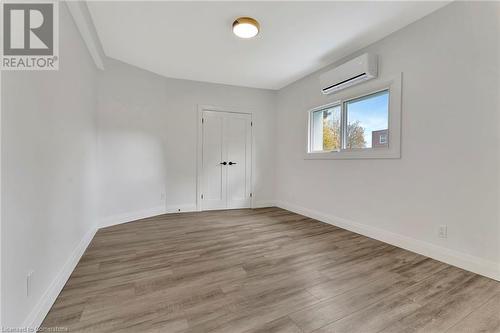 Bedroom in the ADU featuring light wood-type flooring and an AC wall unit - 306 Paling Avenue, Hamilton, ON - Indoor Photo Showing Other Room