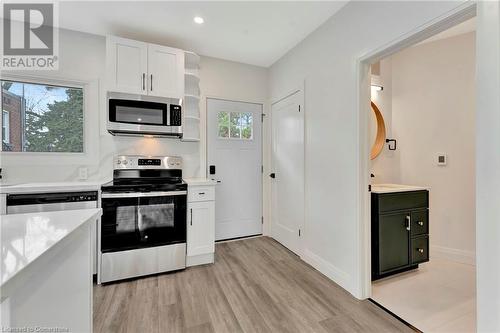 Kitchen in the ADU featuring white cabinetry, light hardwood / wood-style flooring, and stainless steel appliances - 306 Paling Avenue, Hamilton, ON - Indoor Photo Showing Kitchen