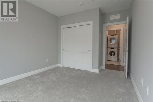 Unfurnished bedroom with stacked washer / drying machine, light carpet, and a closet - 460 Callaway Road Unit# 910, London, ON - Indoor