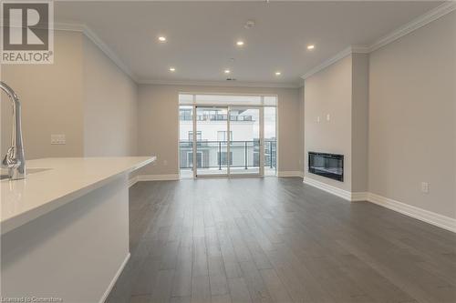 Unfurnished living room featuring dark hardwood / wood-style floors and ornamental molding - 460 Callaway Road Unit# 910, London, ON - Indoor With Fireplace