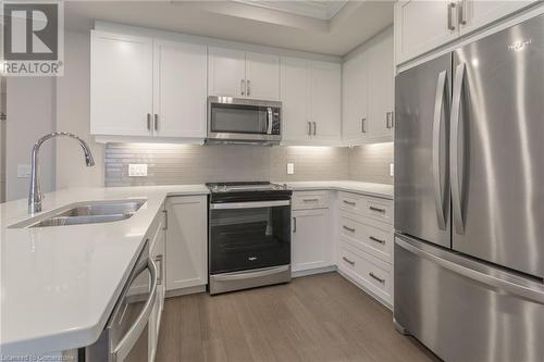 Kitchen with hardwood / wood-style flooring, sink, white cabinets, and appliances with stainless steel finishes - 460 Callaway Road Unit# 910, London, ON - Indoor Photo Showing Kitchen With Double Sink With Upgraded Kitchen