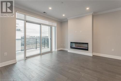 Unfurnished living room featuring crown molding and dark wood-type flooring - 460 Callaway Road Unit# 910, London, ON - Indoor With Fireplace