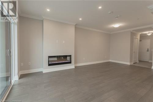 Unfurnished living room featuring light hardwood / wood-style floors and ornamental molding - 460 Callaway Road Unit# 910, London, ON - Indoor With Fireplace