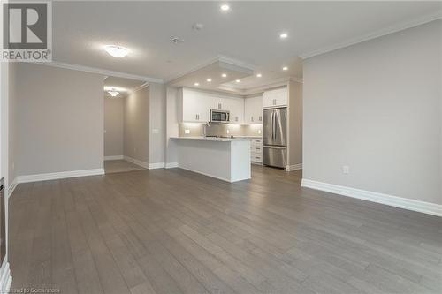 Kitchen with kitchen peninsula, stainless steel appliances, white cabinetry, and hardwood / wood-style flooring - 460 Callaway Road Unit# 910, London, ON - Indoor Photo Showing Kitchen