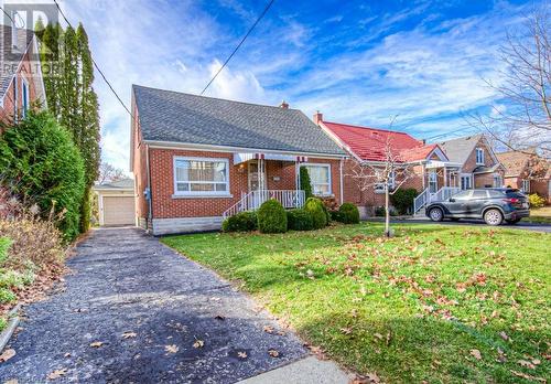 1.5 storey home featuring a front lawn, an outdoor structure, and a garage - 55 Ellis Avenue, Kitchener, ON - Outdoor With Facade