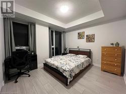 Bedroom with light hardwood / wood-style floors, a raised ceiling, and a textured ceiling - 