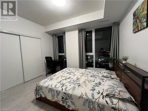 Bedroom with light hardwood / wood-style floors, a textured ceiling, and a closet - 55 Duke Street W Unit# 1607, Kitchener, ON - Indoor Photo Showing Bedroom