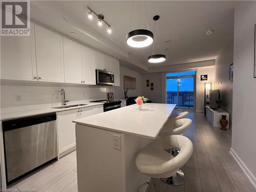 Kitchen with white cabinetry, a center island, sink, pendant lighting, and appliances with stainless steel finishes - 55 Duke Street W Unit# 1607, Kitchener, ON - Indoor Photo Showing Kitchen With Stainless Steel Kitchen With Double Sink