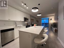 Kitchen with white cabinetry, a center island, sink, pendant lighting, and appliances with stainless steel finishes - 