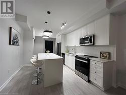 Kitchen with pendant lighting, white cabinets, sink, a kitchen island, and stainless steel appliances - 