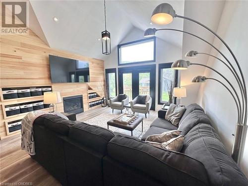 Living room with wood walls, wood-type flooring, high vaulted ceiling, and a tiled fireplace - 796363 Grey 19 Road, The Blue Mountains, ON - Indoor Photo Showing Living Room With Fireplace