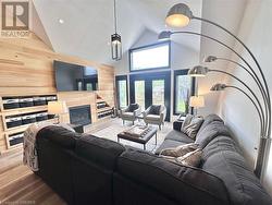 Living room with wood walls, wood-type flooring, high vaulted ceiling, and a tiled fireplace - 